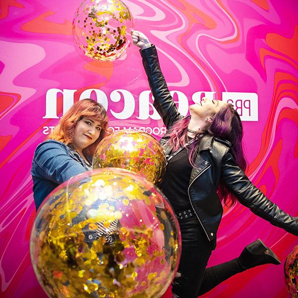 http://x1v.businessflowerdelivery.com/wp-content/uploads/2023/06/two-women-holding-balloons-in-front-of-a-pink-pba-beacon-wall.jpg